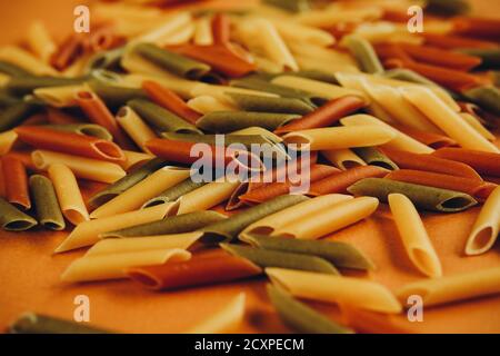 Cadre composé de pâtes vertes, jaunes et rouges de penne colorées naturellement avec de la tomate et des épinards. Concept des produits non périssables. Banque D'Images