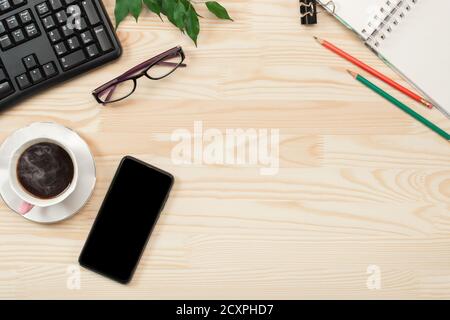 Vue de dessus sur une table de bureau en bois et une tablette téléphonique noire. Espace de travail, bureau avec café et ordinateur, fournitures de bureau avec espace de photocopie Banque D'Images