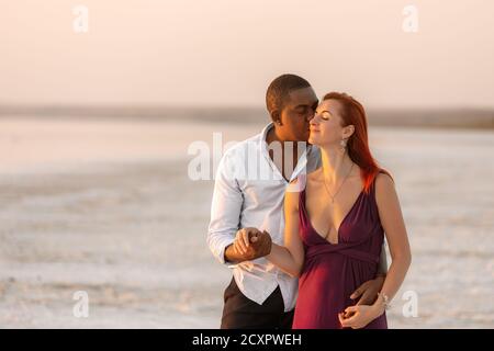 Couple multiracial embrassant et embrassant sur une plage. Beau moment romantique entre deux amoureux. Le concept de l'amour Banque D'Images