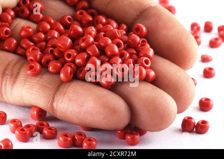 Gros plan photo de la main d'une femme avec des perles sur fond blanc. Macro, utilisé dans la finition des vêtements de mode. Faire collier de perles, perles pour femme de fashi Banque D'Images