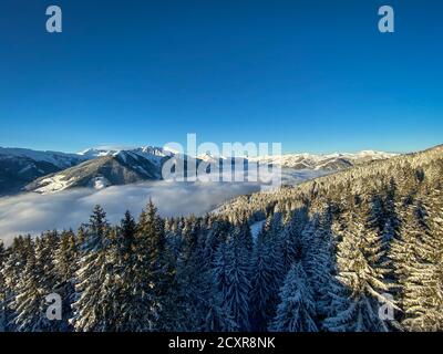 Vue panoramique sur les montagnes enneigées de la région de ski De Saalbach Hinterglemm dans les alpes autrichiennes sous une couverture de nuages contre ciel bleu dans le Banque D'Images