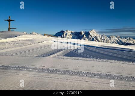 Vue panoramique sur les montagnes enneigées de Leogang avec croix De Wildenkarkogel tôt le matin contre le ciel bleu Banque D'Images