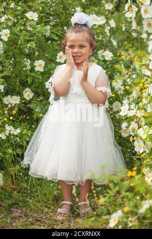 Une petite fille dans une robe blanche de la mariée dans la nature. Banque D'Images