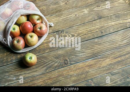 Pommes biologiques dans un sac en maille textile écologique réutilisable sur fond de bois. Concept zéro déchet, style de vie sans plastique. Vue de dessus, espace de copie Banque D'Images