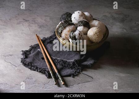 Bol avec différentes tailles de boules de riz et sésame noir avec des Algues Nori, servi avec des œufs durs, de la sauce de soja, des baguettes sur le tableau gris. Asian sty Banque D'Images