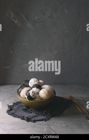 Bol avec différentes tailles de boules de riz et sésame noir avec des Algues Nori, servi avec des œufs durs, de la sauce de soja, des baguettes sur le tableau gris. Asian sty Banque D'Images
