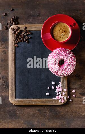 Tableau vintage vide, rose vitrage beigne, le sucre, les grains de café et tasse de café noir rouge sur fond de bois ancien. Vue de dessus avec l'espace pour le texte. Banque D'Images