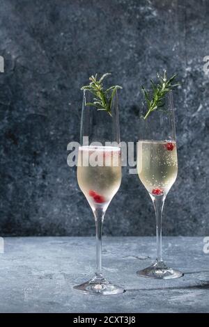 Deux verres de champagne blanc servi avec des fruits rouges et du romarin sur blue texture background. Copy space Banque D'Images