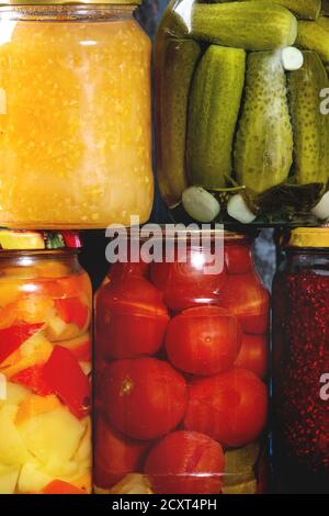 Variété de pots en verre de légumes marinés ou fermentés faits maison et confitures en rangée avec vieux fond de bois bleu foncé. Conserves saisonnières. Fermer u Banque D'Images