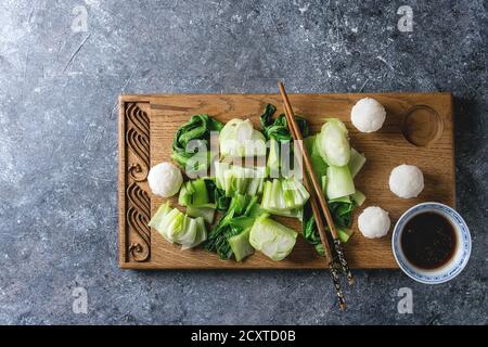 Sauté de bok choy ou chou chinois avec de la sauce soja et de boules de riz servi sur planche à découper en bois décoratif avec des baguettes sur la texture gris backg Banque D'Images