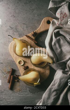 Dessert traditionnel confit de poires au vin blanc servi dans des bols en verre avec le sirop et les zestes de citron sur le bord en bois servant plus de texture gris table. Top v Banque D'Images