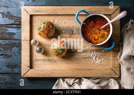 Casserole de soupe de betteraves bortsch traditionnel avec de la crème sure et de la coriandre fraîche servi avec du pain à l'ail pain pampushki, sur le plateau de bois avec du linge de maison Banque D'Images