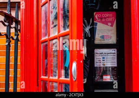 Londres, Royaume-Uni - 14 septembre 2017 : célèbre boîte téléphonique rouge avec une personne à l'intérieur. Informations utiles sur les appels à l'intérieur de la boîte. Banque D'Images