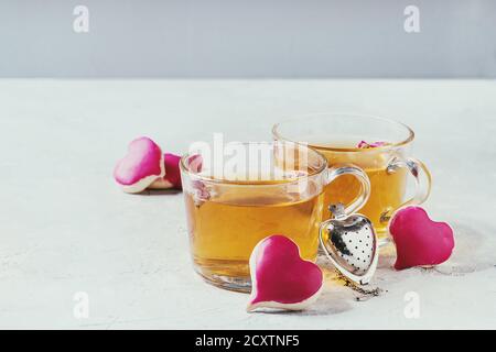 L'amour Saint Valentin carte de souhaits avec deux verres de thé chaud et des biscuits en forme de coeur avec glaçage rose et d'un plateau de table blanc sur la crépine. Copie Banque D'Images