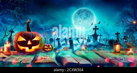 Jack O’ Lantern on Table dans un cimetière piquant la nuit - Halloween avec pleine lune Banque D'Images