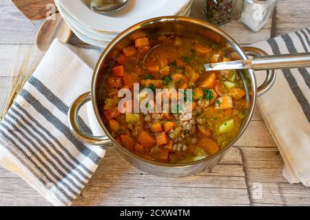 soupe de légumes avec viande hachée dans une casserole avec louche sur une table en bois Banque D'Images