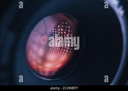 Gros plan sur un magnifique objectif sur fond sombre et lumineux à réflexion rouge. Vue macro. Banque D'Images