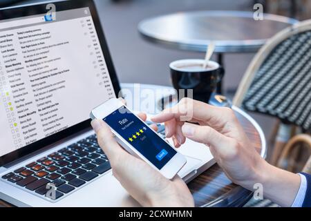 Personne d'affaires au café envoyant une enquête de satisfaction client sur écran d'application pour smartphone avec interface proposant d'évaluer l'expérience avec star i Banque D'Images