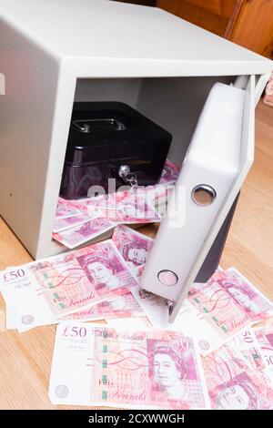 Coffre-fort et caisse-caisse installés sur les planchers et débordant de billets britanniques de cinquante livres. Banque D'Images