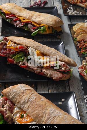 Délicieux sandwiches à la viande et variété d'ingrédients sur une table en bois Banque D'Images