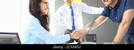 Hommes d'affaires et femmes d'affaires dans leur bureau souriant et serrant la main Banque D'Images