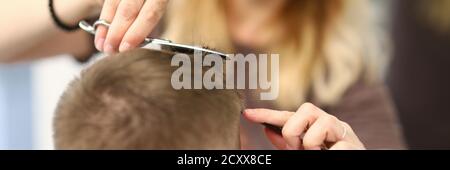 Une femme coiffante coupe les cheveux de l'homme dans un salon de beauté Banque D'Images