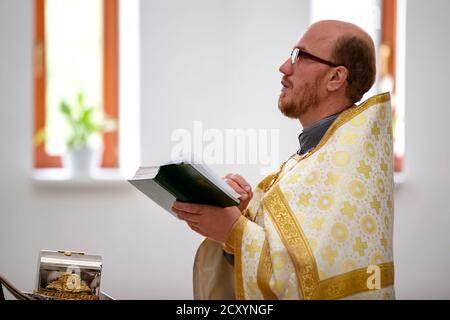 15 juillet 2020 Bélarus, ville de Gomel. L'église de la ville. Le prêtre lit une prière avec la Bible entre ses mains. Banque D'Images