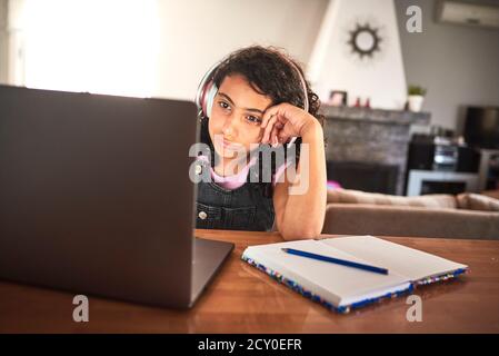 Gros plan d'une fille ennuyeuse qui fait ses devoirs avec son ordinateur portable à la maison. Étudier le concept Banque D'Images