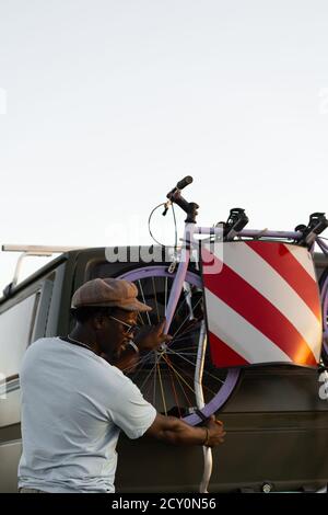 Homme noir afro-américain avec un vélo dans son campeur fourgonnette Banque D'Images
