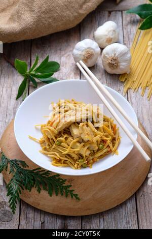 Cuisine asiatique - nouilles de Bami goreng sur fond rustique et baguettes Banque D'Images