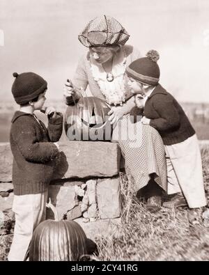 1920 FEMME HABILLÉE DE FAÇON TENDANCE MÈRE SCULPTANT HALLOWEEN CITROUILLE COMME ENFANTS DEUX GARÇONS PORTANT DES CHAPEAUX EN LAINE ET DES CHANDAILS EN TRICOT MONTRE - H11 HAR001 HARS VIEUX TEMPS NOSTALGIE VIEILLE MODE 1 JUVÉNILE STYLE SCULPTANT FILS FAMILLES MODE DE VIE FEMMES RURAL MAISON VIE LAINE COPY SPACE AMITIÉ FEMMES FILLES PERSONNES HOMMES B&W KNIT LES BUTS BROCHE CITROUILLES ET L'EXCITATION BAS ANGLE COMME LES CHANDAILS TENDANCE CASQUETTES ÉLÉGANT CAMEO OCTOBRE CRÉATIVITÉ JACK-O-LANTERNE JEUNES MI-ADULTE FEMME MI-ADULTE MAMANS OCTOBRE 31 TOGETHNESS NOIR ET BLANC RACE BLANCHE HAR001 DÉMODÉE Banque D'Images