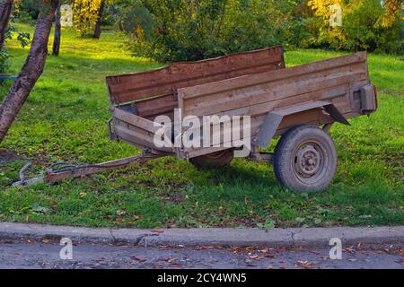 Une vieille remorque de voiture se trouve sur la pelouse verte. Ancienne remorque de voiture ouverte. Banque D'Images