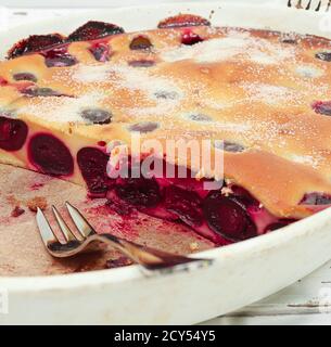 Tarte aux cerises clafoutis - tarte traditionnelle française dans un blanc plat de cuisson avec une fourchette en gros plan Banque D'Images