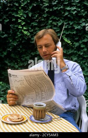 ANNÉES 1990, HOMME D'AFFAIRES TRÈS OCCUPÉ PRENANT LE PETIT-DÉJEUNER ASSIS EN TRAIN DE MANGER À L'EXTÉRIEUR UN JOURNAL ET PARLER AU TÉLÉPHONE MULTITÂCHE - KS32545 NET002 HARS COMMUNICATION JEUNES ADULTES INFORMATION STYLE DE VIE HISTOIRE GROGNUP VIE À LA MAISON COMMUNICATION ESPACE DE COPIE DEMI-LONGUEUR PERSONNES HOMMES MATIN VENDRE GRAND ANGLE DÉCOUVERTE PRÉCOCE ET LA MISE EN RÉSEAU DE LA NUTRITION DE CONNAISSANCES SUR LES TÉLÉPHONES D'OPPORTUNITÉ CONNEXION MULTITÂCHE TÉLÉPHONES CELLULE CONSOMMER CONSOMMER NOURRITURE COOPÉRATION VENDEURS STOCK MARCHÉ MONTRE POIGNET JEUNE ADULTE HOMME VIEUX MODE Banque D'Images