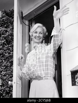 FEMME SOURIANTE DES ANNÉES 1970 FEMME AU FOYER DEBOUT DANS LA PORTE OUVERTE DE LA MAISON BONJOUR AU REVOIR - S20496 HAR001 HARS SANTÉ MAISON VIE COPIE ESPACE AMITIÉ DEMI-LONGUEUR FEMMES PERSONNES CONFIANCE BIENVEILLANTE GESTANTE B&W FEMME AU FOYER BONJOUR BONHEUR HOMEMAKERS GAI HELLO EXTÉRIEUR BAS ANGLE FIERTÉ CHEMISIER GESTES FEMMES AU FOYER SOURIT CONNEXION JOYEUSE ÉLÉGANT MI-ADULTE MOYENNE-ADULTE FEMME NOIRE ET L'ETHNIE BLANCHE CAUCASIENNE HAR001 ANCIEN MODE Banque D'Images