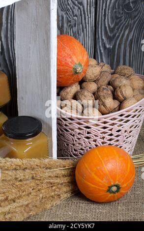 Confiture de fruits en pots. Se tient dans une caisse en bois peinte en blanc. À côté, il y a un panier de noix, une citrouille d'orange et un bouquet d'herbes sèches. Banque D'Images