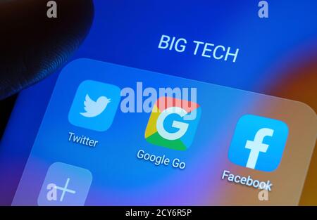 Google, Facebook, Twitter applications affichées à l'écran et doigt flou pointant vers elles. Banque D'Images