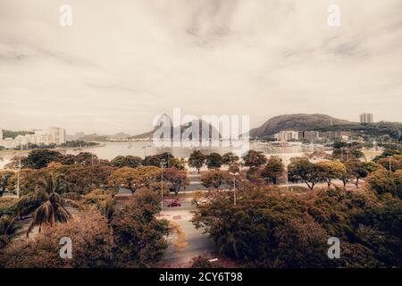 Drone grand angle tourné d'un district de Botafogo à Rio de Janeiro, au Brésil; avec plusieurs palmiers et d'autres arbres tropicaux au premier plan, une baie avec sai Banque D'Images