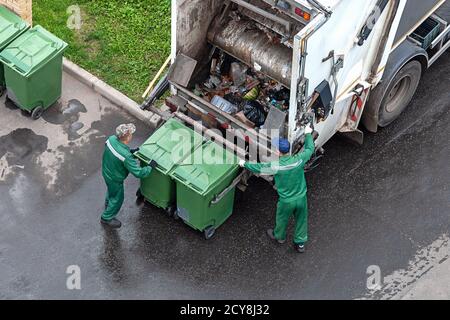 deux travailleurs chargent des déchets domestiques mélangés dans un camion de collecte des déchets Banque D'Images