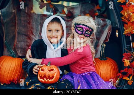 Trick ou tronc. Enfants célébrant Halloween dans le coffre de la voiture. Garçon et fille avec des citrouilles rouges célébrant les fêtes traditionnelles d'octobre en plein air. Coffre-fort a Banque D'Images