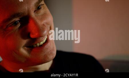 Un jeune homme avec un regard sérieux. Homme froid dans les tons rouges mal sourire Banque D'Images