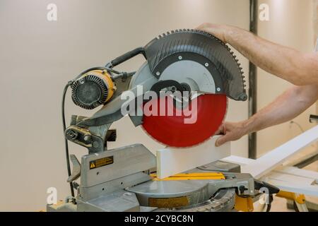 Une scie circulaire d'un ouvrier coupant une planche de moulage en bois à une construction Banque D'Images