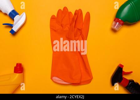 moyens de nettoyage de la maison sur fond jaune. gants en caoutchouc orange au centre. Banque D'Images