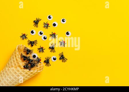 Araignées et mouches noires, yeux gogly rampent hors de glace cône sur fond jaune vue du dessus Flat Lay Happy Halloween Creative concept carte de vacances Banque D'Images