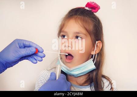 Médecin effectuant un test de coronavirus pour une fille patient. Test d'ADN. Collecte de mucus de la gorge pour la recherche en laboratoire. Prélèvement d'un échantillon de salive Banque D'Images