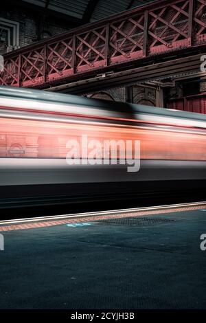 Prises de vue cinématographiques en longue exposition du réseau de trains souterrains dans Londres à une station de plein air avec des lumières vives Banque D'Images