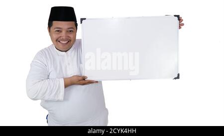 souriant musulman asiatique avec un surpoids debout et tenant le tableau blanc présentant un espace coppy. Banque D'Images