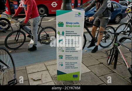 Résidents locaux à vélo à Whitechapel, avec des panneaux conseillant de garder la distance sociale sécuritaire en raison de la pandémie de coronavirus / Covid-19 à Londres, Angleterre, Royaume-Uni Banque D'Images