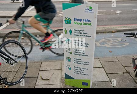 Résidents locaux à vélo à Whitechapel, avec des panneaux conseillant de garder la distance sociale sécuritaire en raison de la pandémie de coronavirus / Covid-19 à Londres, Angleterre, Royaume-Uni Banque D'Images