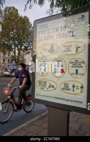 Résidents locaux à vélo à Whitechapel, avec des panneaux conseillant de garder la distance sociale sécuritaire en raison de la pandémie de coronavirus / Covid-19 à Londres, Angleterre, Royaume-Uni Banque D'Images